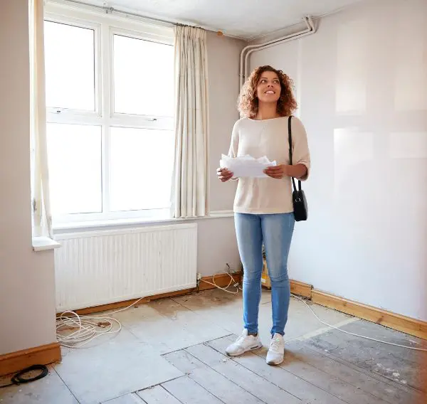 First-time buyer standing in renovation property with house plans, representing buying your first home in Scotland