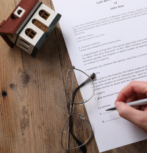 Person signing a disputed will with spectacles and miniature house nearby