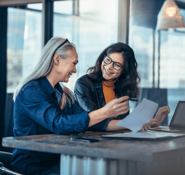 Two women reviewing documents at a table, symbolising transfer of property title in Scotland