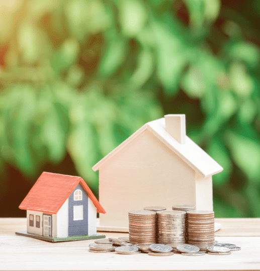 Two small model houses beside stacked coins representing property taxes in Scotland