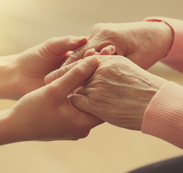 Younger hands holding the hands of an older adult, representing care and support with guardianship in Scotland.