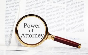 Magnifying glass highlighting the words ‘Power of Attorney’ on a legal document.