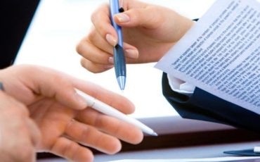 Person signing a commercial contract agreement during business negotiations