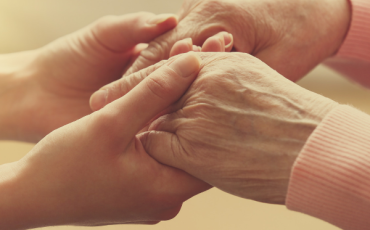 Younger hands holding the hands of an older adult, representing care and support with guardianship in Scotland.