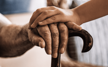 Younger hand supporting older hand — symbolising financial guardianship and caring for adults with incapacity in Scotland