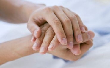Relative holding the hand of an adult lacking capacity, symbolising guardianship and support in Scotland