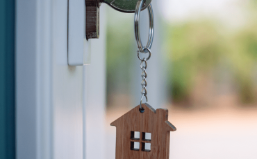 House key in a door with a house-shaped keyring, symbolising homeownership and property purchase in Scotland